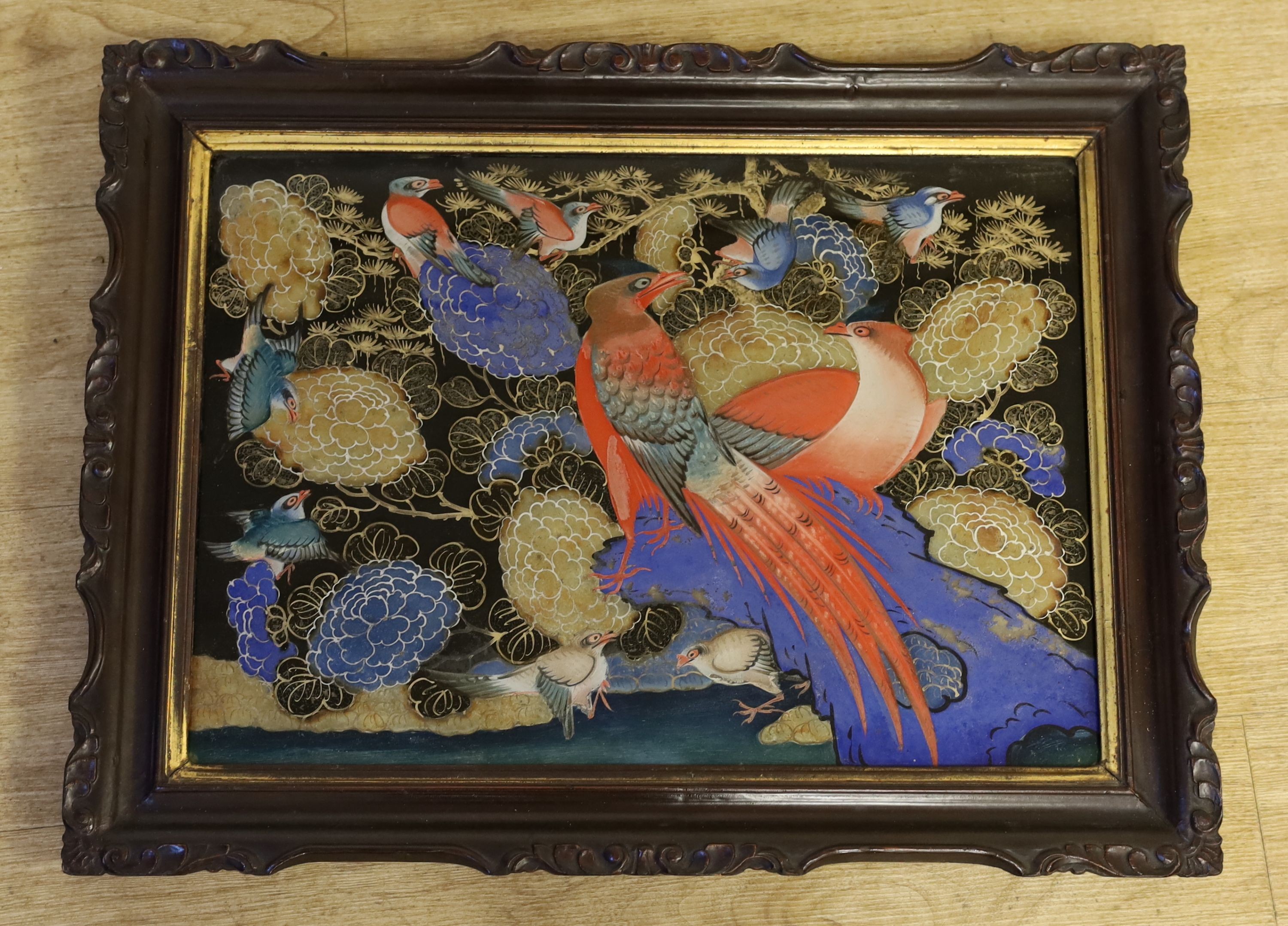 An unusual Korean reverse painted glass picture, 19th century, decorated with colourful birds amid flowers on a black ground, in original lacquered wood frame, 35 x 50cm